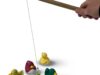 Eine Hand hält einen Holzstab an dem ein Faden mit Magnet ist. Des Weiteren sind 5 bunte Kunststoffenten zu sehen.
