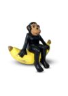 Dekoobjekt: Eine gelbe Banane, auf der ein schwarzer Affe sitzt
